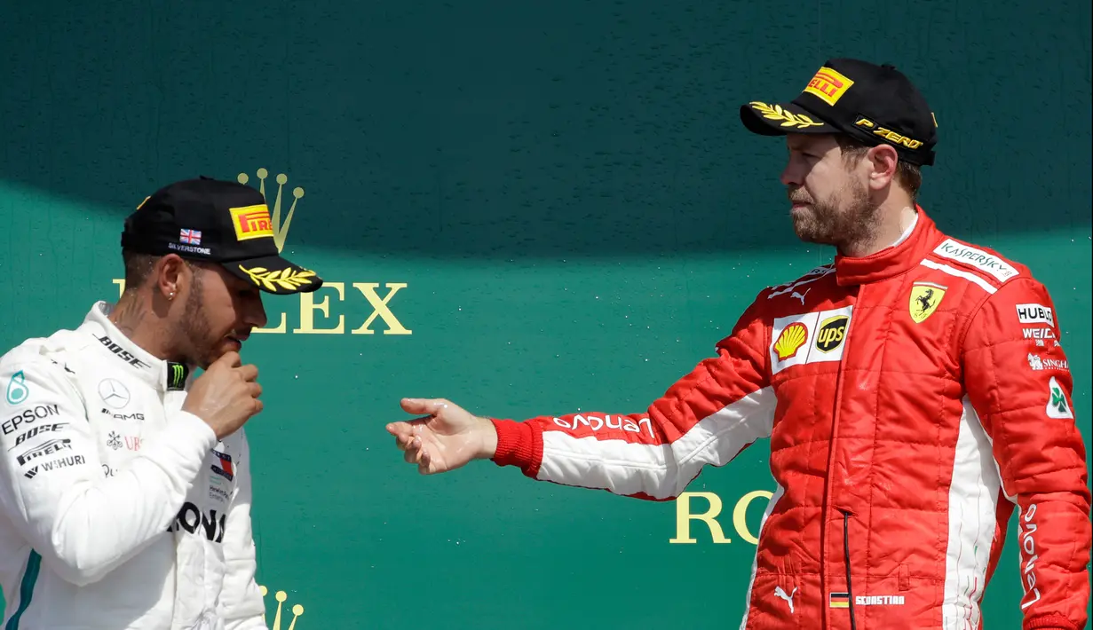 Pembalap Ferrari, Sebastian Vettel (kanan) mengulurkan tangannya ke arah pembalap Mercedes, Lewis Hamilton usai memenangkan F1 GP di Sirkuit Silverstone, Inggris, Minggu (8/7). Vettel berhasil mengungguli Lewis Hamilton. (AP Photo/Luca Bruno)