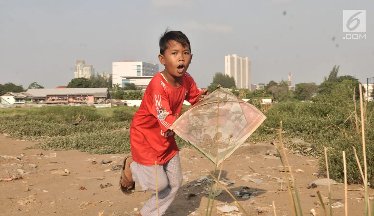 Anak-anak bermain layang-layang di tanah sengketa kawasan Pedongkelan, Jakarta, Kamis (11/7/2019). Meski bertempat tinggal di atas lahan sengketa, anak-anak setempat memanfaatkan tanah kosong yang penuh semak belukar tersebut sebagai sarana bermain ketika sore hari. (merdeka.com/Iqbal S. Nugroho)