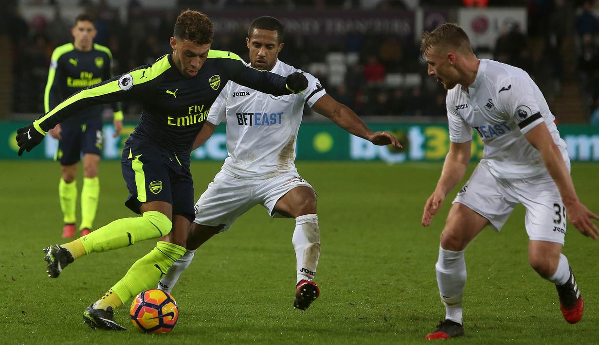 Gelandang Arsenal, Alex Oxlade-Chamberlain, berusaha melewati hadangan pemain Swansea. Meski bermain tandang, The Gunners sudah tampil menyerang sejak babak pertama baru dimulai. (AFP/Geoff Caddick)