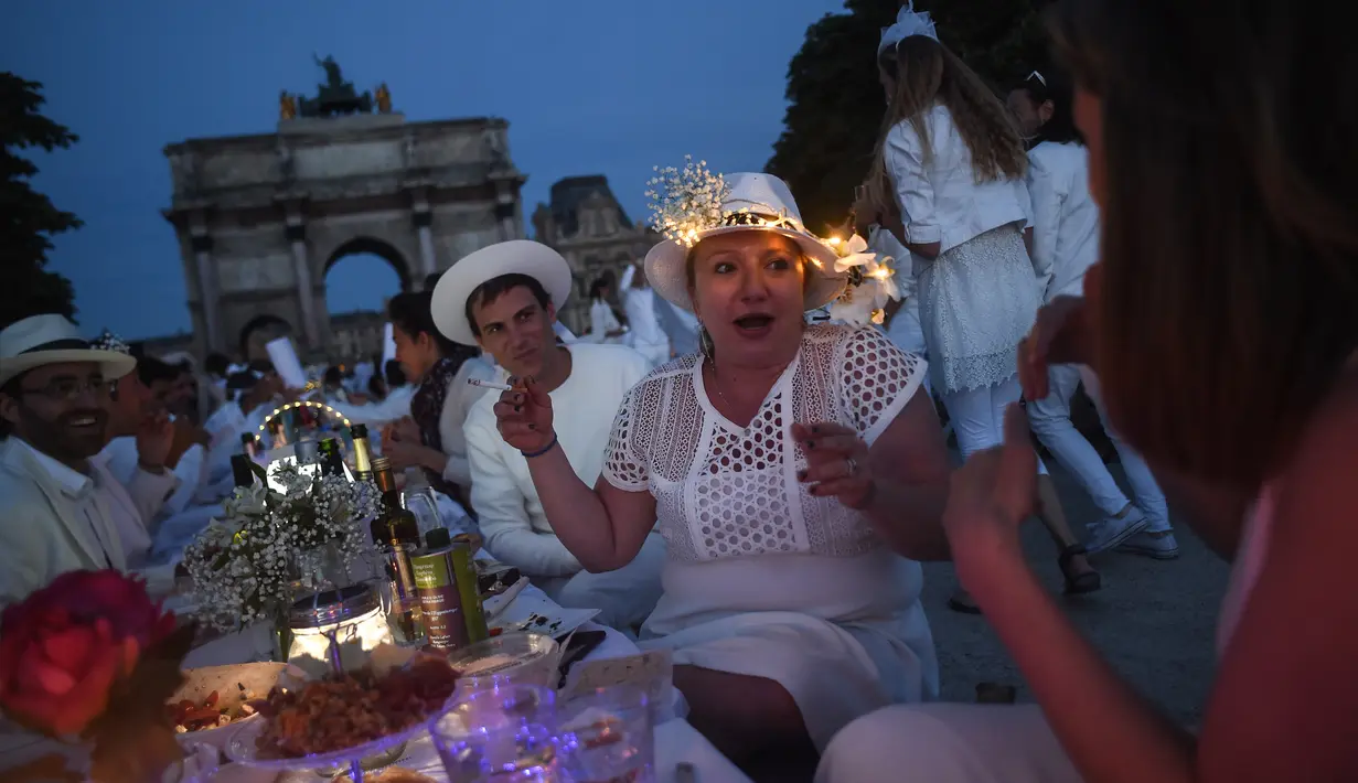 Peserta dalam balutan serba putih  berkumpul untuk Dinner en Blanc atau "makan malam putih" di Tuileries Gardens, Paris, Kamis (6/6/2019). Tahun 2015, sekitar 70 kota di lebih dari 35 negara telah atau akan mengadakan Diner en blanc, seperti Johannesburg, Montreal dan Tokyo. (Lucas BARIOULET/AFP)