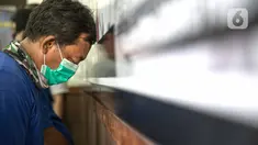 Tersangka kasus pemalsuan surat hasil rapid test COVID-19 tertunduk saat dihadirkan dalam rilis di Mapolres Jakarta Pusat, Minggu (20/12/2020). Polisi mengungkap calo pemalsuan surat hasil rapid test COVID-19 bagi calon penumpang kereta di Stasiun Senen. (Liputan6.com/Faizal Fanani)