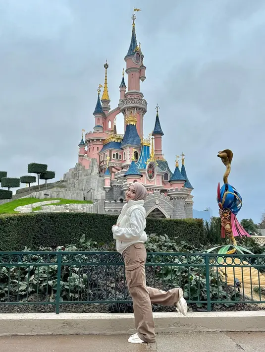 Ide outfit bermain di theme park ala Putri Delina. Ia mengenakan puffer jacket putih, dipadu cargo pants cokelat, hijab cokelat muda yang serasi. [Foto: Instagram/putridelinaa]
