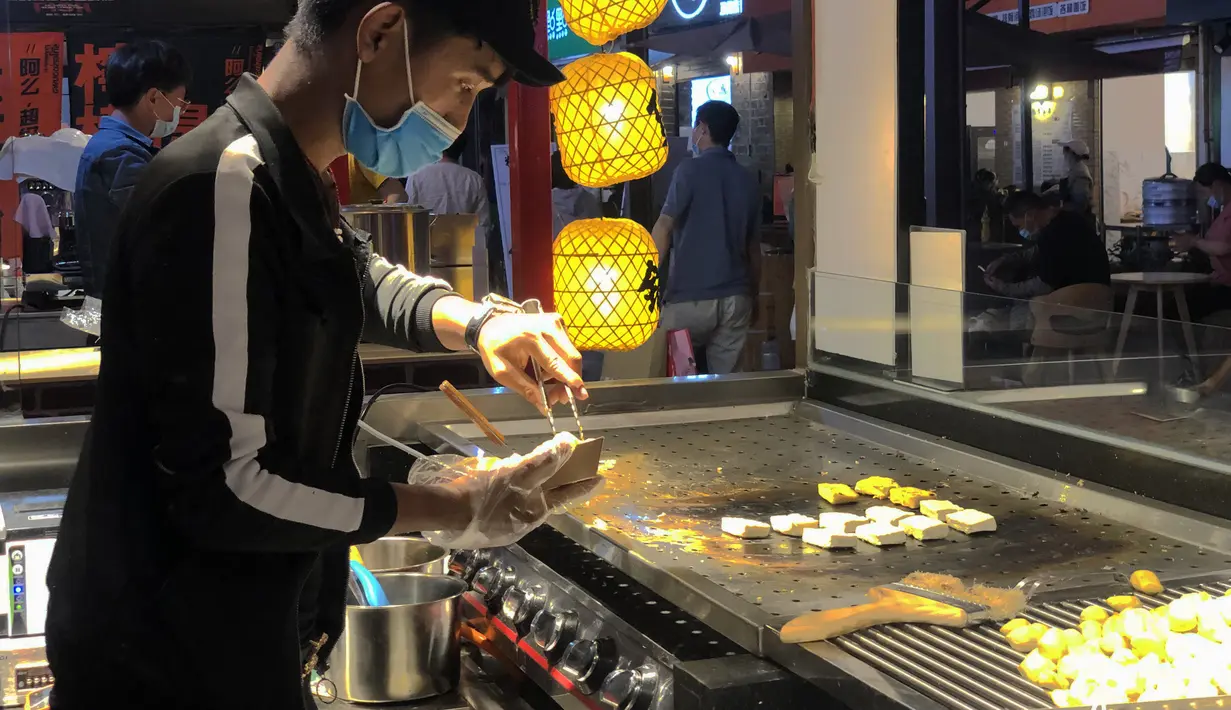Seorang pedagang menjual kudapan di jalur pejalan kaki di Kunming, Provinsi Yunnan, China barat daya, pada 15 Maret 2020. Pemerintah Kota Kunming telah mengizinkan restoran-restoran untuk membuka kembali layanan makan di tempat di bawah upaya ketat pencegahan COVID-19. (Xinhua/Ding Yiquan)