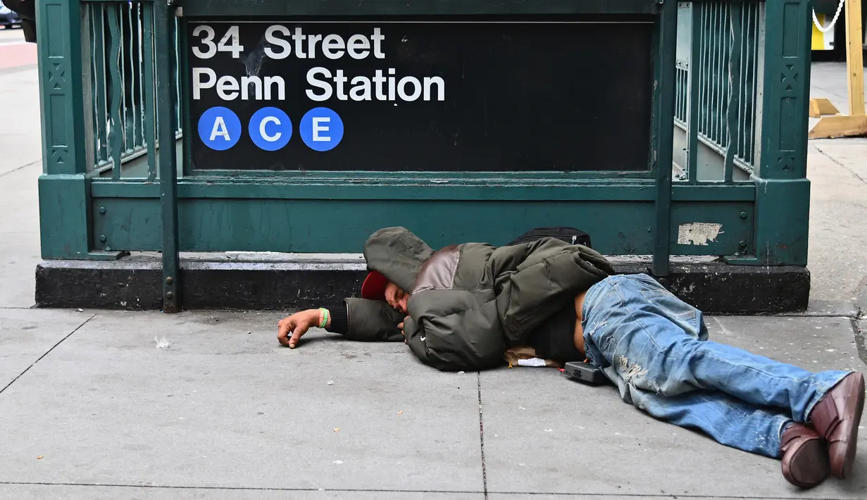 Seorang pria tidur di dekat Penn Station di Madison Square Gardens, New York City pada Kamis (17/9/2020). Sejak pandemi virus corona, para tunawisma kini  lebih terlihat seiring banyaknya penutupan banyak tempat penampungan karena alasan kesehatan. (Angela Weiss / AFP)