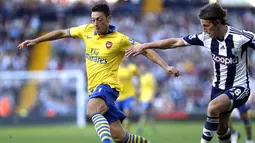 Gelandang Arsenal Mesut Ozil (kiri) berusaha melewati bek West Bromwich Albion Billy Jones (kanan) pada pertandingan sepak bola Liga Inggris antara West Bromwich Albion vs Arsenal  di The Hawthorns, West Bromwich (06/10/13). (AFP/Adrian Dennis).