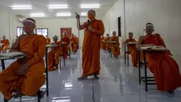 Para biksu muda mengenakan masker dan pelindung wajah saat belajar agama di Molilokayaram Educational Institute, Bangkok, Thailand, Rabu (15/4/2020). Sekitar 200 biksu muda tetap bersekolah kendati Thailand menutup semua sekolah selama lockdown akibat COVID-19. (AP Photo/Gemunu Amarasinghe)