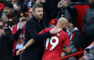 Pelatih interim Manchester United, Michael Carrick, memberi ucapan selamat kepada gelandang asal Kamerun Bryan Mbeumo saat meninggalkan lapangan setelah ditarik keluar dalam pertandingan Liga Inggris antara Manchester United dan Manchester City di Old Trafford, Manchester, Sabtu (17/1/2026). (Darren Staples / AFP)