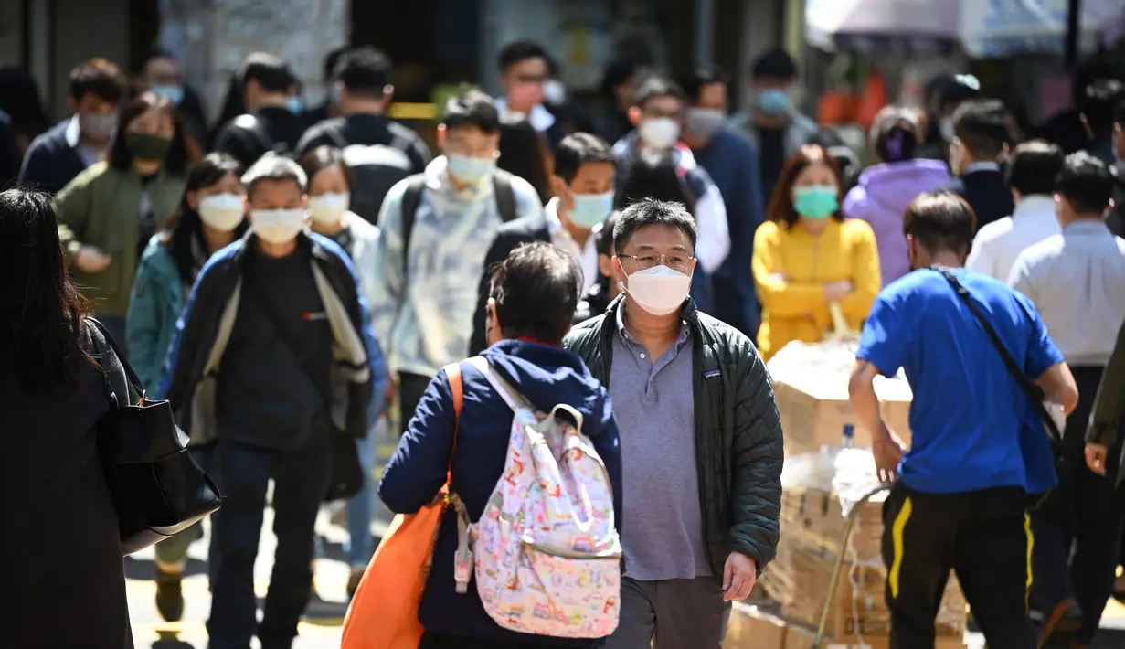 Orang-orang memakai masker di jalan di Hong Kong pada 27 Februari 2023. Perpanjangan mandat masker  tersebut menyeret terjadi saat kota tersebut akan menjadi tuan rumah sejumlah acara global, seperti turnamen golf World City Championship dan Museum Summit 2023, menjadikannya bulan tersibuk dalam lebih dari tiga tahun. (AFP/Peter Parks)