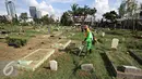 Pekerja membersihkan makam di TPU Karet Bivak, Jakarta, Rabu (4/5). Dinas Pertamanan dan Pemakaman DKI Jakarta menerapkan sistem online pelayanan pemakaman di 77 taman pemakaman umum (TPU). (Liputan6.com/Immanuel Antonius) 