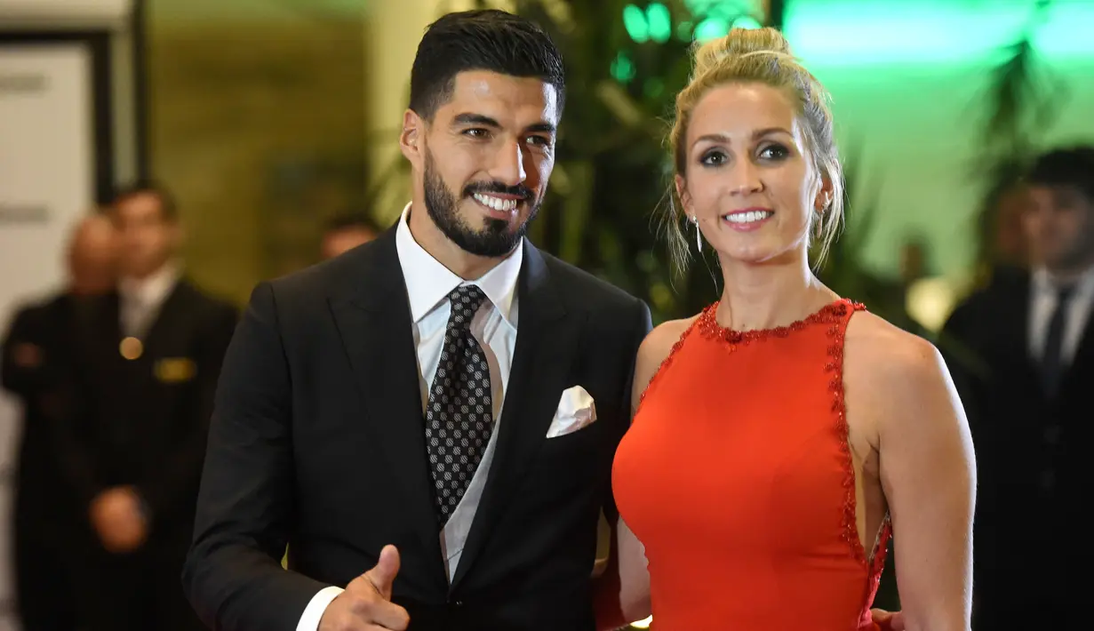 Pemain Barcelona, Luis Suarez dan istrinya Sofia Balbi berpose di karpet merah saat menghadiri pernikahan Lionel Messi di Rosario, Argentina (30/6). (AFP Photo/Eitan Abramovich)