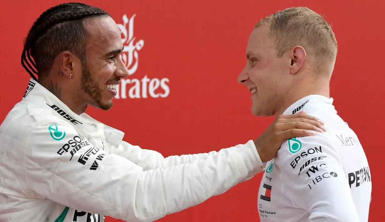 Juara F1 GP Jerman, pembalap Mercedes Lewis Hamilton bersama pembalap Ferrari dari Finlandia, Vatteri Bottas yang menempati posisi kedua merayakan kemenangan di ats podium Sirkuit Hockenheim, Minggu (22/7). (AP/Jens Meyer)