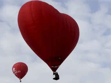 Sebuah balon udara panas berbentuk hati (kanan) terbang di langit selama Love Cup 2016 di Jekabpils, Latvia (14/2). Nikah massal yang diikuti oleh 50 pasangan ini menggelar akad di atas 27 balon udara. (REUTERS/Ints Kalnins)