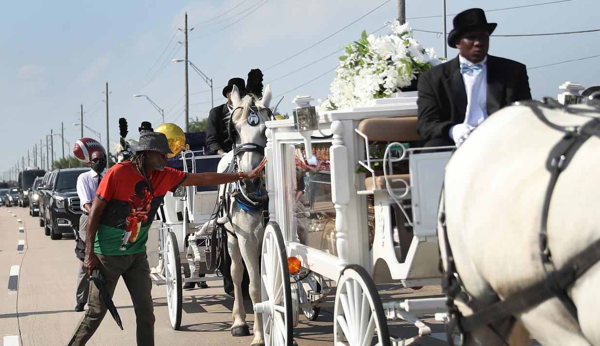 Seorang pria menyentuh kereta kuda yang membawa jenazah George Floyd saat menuju pemakaman Houston Memorial Gardens di Houston, Texas, Amerika Serikat, Selasa (9/6/2020). Floyd akan dimakamkan di samping makam ibunya, Larcenia Floyd. (Joe Raedle/etty Images/AFP)