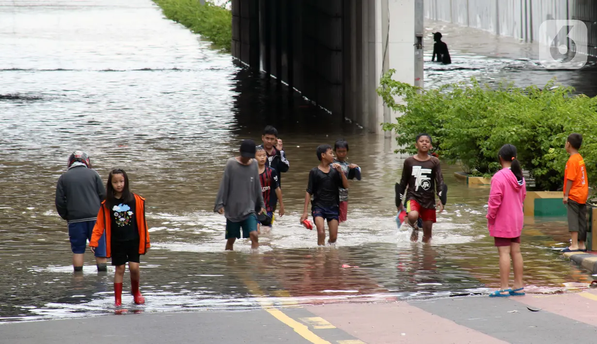 Warga melintasi banjir di terowongan Jalan Angkasa, Jakarta, Selasa (25/2/2020). Hujan yang mengguyur Jakarta sejak Senin (24/2) malam membuat sejumlah kali meluap dan menyebabkan banjir di terowongan tersebut. (Liputan6.com/Helmi Fithriansyah)