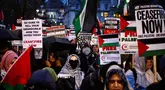 Para demonstran pro-Palestina melambaikan bendera Palestina dan memegang plakat saat berunjuk rasa di Parliament Square, London pada 21 Februari 2024. (HENRY NICHOLLS/AFP)
