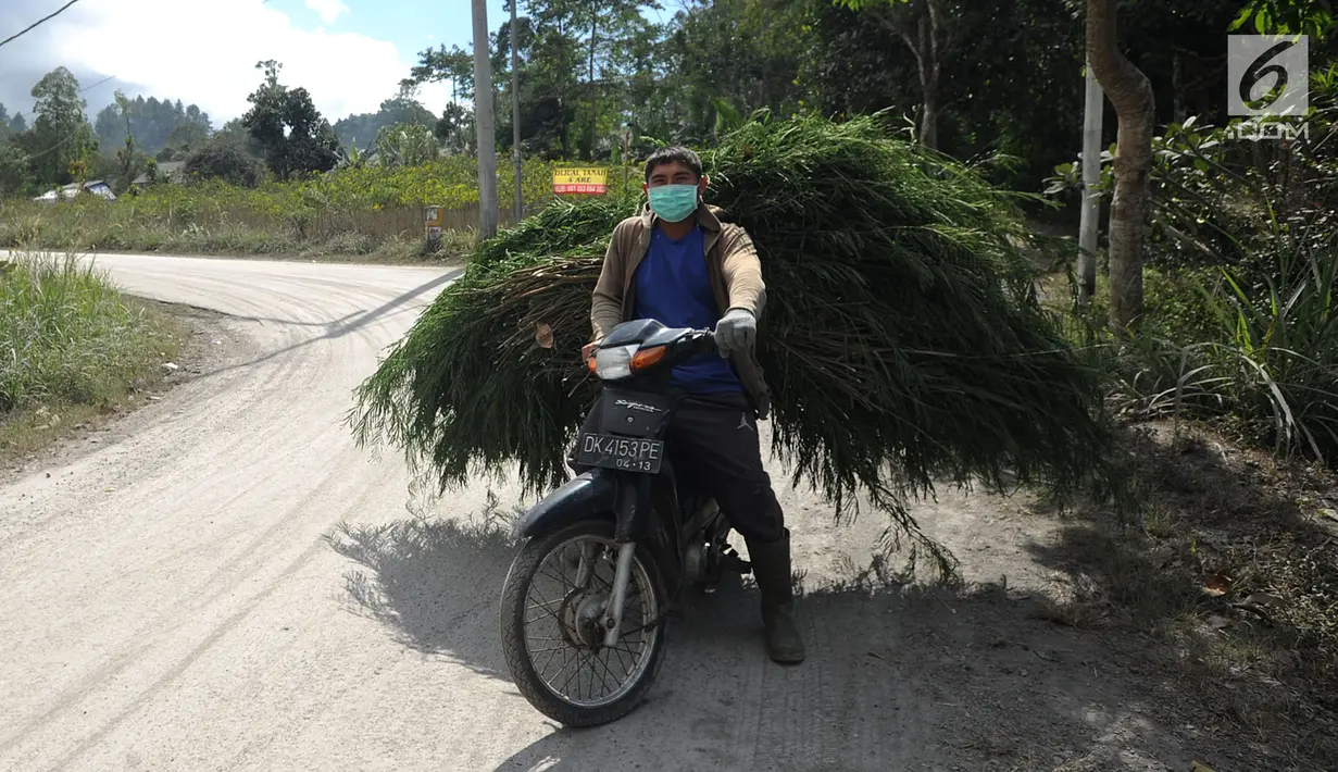 Pengendara sepeda motor mengenakan masker saat melintas di Desa Pempatan, Karangasem, Bali, Sabtu (30/6). Pascaerupsi Gunung Agung, abu vulkanik masih menyelimuti kawasan tersebut. (Merdeka.com/Arie Basuki)