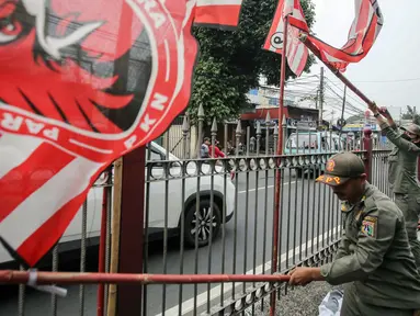 Petugas Satuan Polisi Pamong Praja (Satpol PP) DKI Jakarta menertibkan alat peraga partai politik berbentuk bendera di kawasan Jalan Raya Bogor, Jakarta, Rabu (26/7/2023). Menjelang Pemilu 2024, pemerintah setempat menertibkan sejumlah bendera dan atribut partai politik yang pemasangannya melanggar aturan terutama di sepanjang jalan protokol serta merusak keindahan kota. (Liputan6.com/Faizal Fanani)
