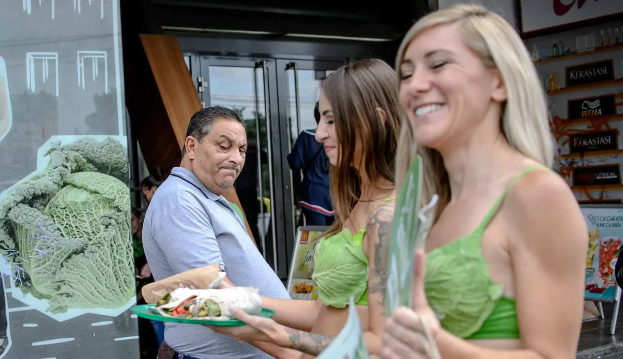 Seorang pria melihat makanan yang dibawa dua aktivis wanita dari PETA saat berkampanye gaya hidup vegan di pusat kota Bucharest, Rumania, (14/8). Kampanye hidup vegan ini akan berlanjut ke negara AS, Rusia da Turki. (AP Photo/Andreea Alexandru)