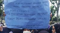 Salah seorang mahasiswi membawa kertas bertuliskan protes terhadap vonis bebas terdakwa pencabulan mahasiswi Universitas Riau. (Liputan6.com/M Syukur)