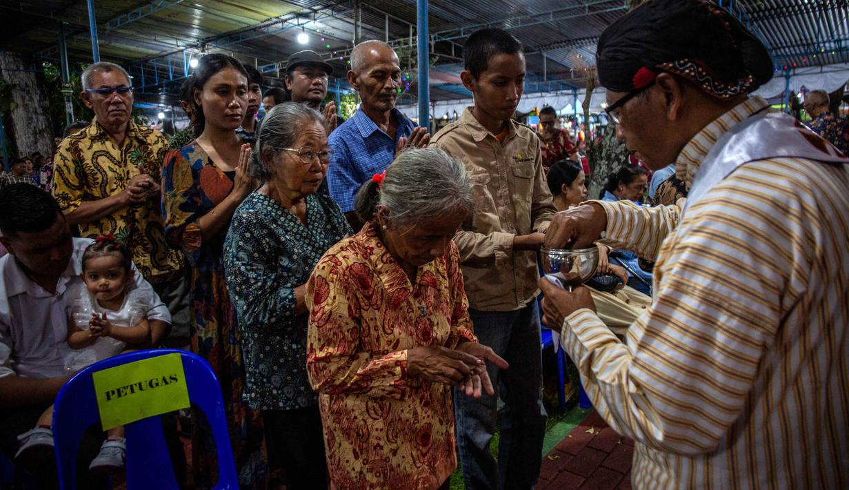 Penggunaan unsur budaya Jawa dalam perayaan keagamaan menjadi ciri khas Gereja Hati Kudus Tuhan Yesus (HKTY) Ganjuran, Bantul, Yogyakarta. Tampak dalam foto, para umat Katolik yang mengenakan pakaian tradisional Jawa menerima Komuni Kudus dari seorang imam selama Misa Malam Natal di Gereja Hati Kudus Yesus di Ganjuran, Bantul, Yogyakarta, pada Rabu 24 Desember 2025. (DEVI RAHMAN/AFP)