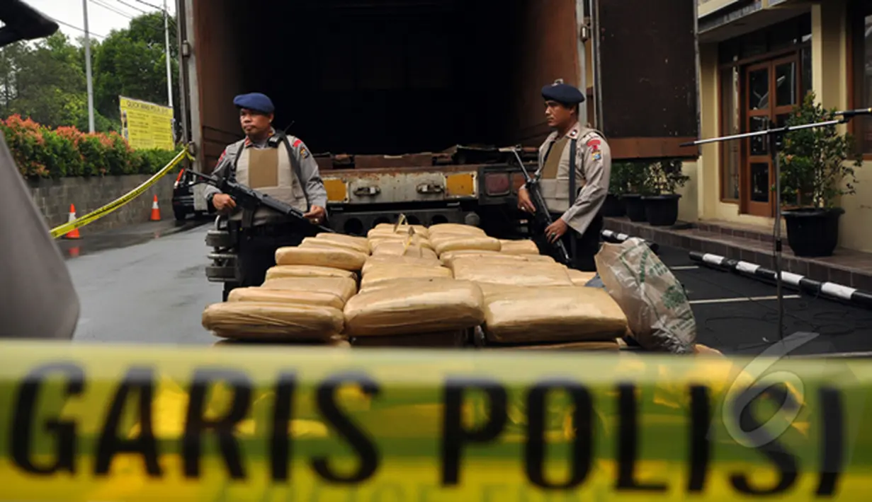 Dua petugas kepolisian saat berjaga di belakang mobil tronton box di Polres Jakarta Barat, Jumat (13/2/2015). Satuan Narkoba Polres Metro Jakarta Barat berhasil mengungkap jaringan peredaran ganja lintas Sumatera ke Jakarta. (Liputan6.com/Faizal Fanani)