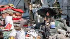 Seorang wanita duduk di samping barang-barang yang diselamatkan dari puing-puing Menara Prajurit Tak Dikenal di kawasan Rimal, Kota Gaza, pada 15 September 2025. (Omar AL-QATTAA/AFP)