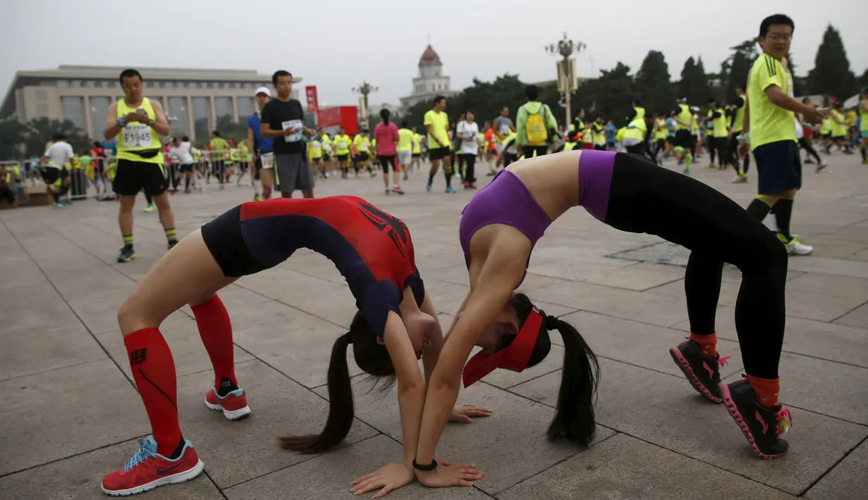 Dua orang peserta meregangkan tubuh mereka jelang mengikuti Beijing International Marathon di Beijing, China, Minggu (20/9/2015). Sekitar 30.000 pelari ikut ambil bagian dalam acara yang berlangsung tiap tahun. (REUTERS/Kim Kyung-Hoon)