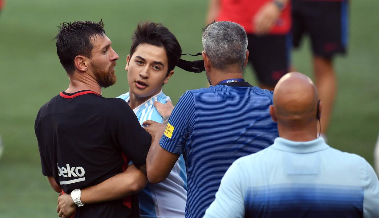 Seorang fans masuk ke lapangan memeluk pemain Barcelona, Lionel Messi, saat latihan di Red Bull Arena, New Jersey, Jumat (21/7/2017). Latihan ini dilakukan jelang laga ICC 2017 melawan Juventus. (AFP/Jewel Samad)