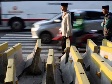 Pejalan kaki menghindari beton pembatas jalan yang diletakkan di atas trotoar Jalan Medan Merdeka Utara, Jakarta, Kamis (25/7/2019). Pembatas jalan yang berada tidak pada tempatnya mengganggu kenyamanan pejalan kaki yang melintasi trotoar jalan tersebut. (Liputan6.com/Helmi Fithriansyah)