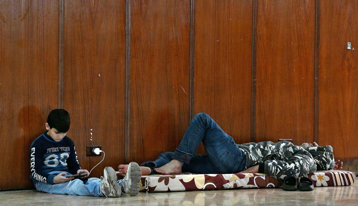 Pergerakan warga ini terjadi setelah Israel mengeluarkan perintah evakuasi bagi penduduk di Lebanon selatan. Tampak dalam foto, orang-orang duduk di dalam sebuah sekolah yang diubah menjadi tempat penampungan bagi para pengungsi di kota Dekwaneh, utara Beirut, Lebanon, pada Kamis 5 Maret 2026. (Joseph EID/AFP)