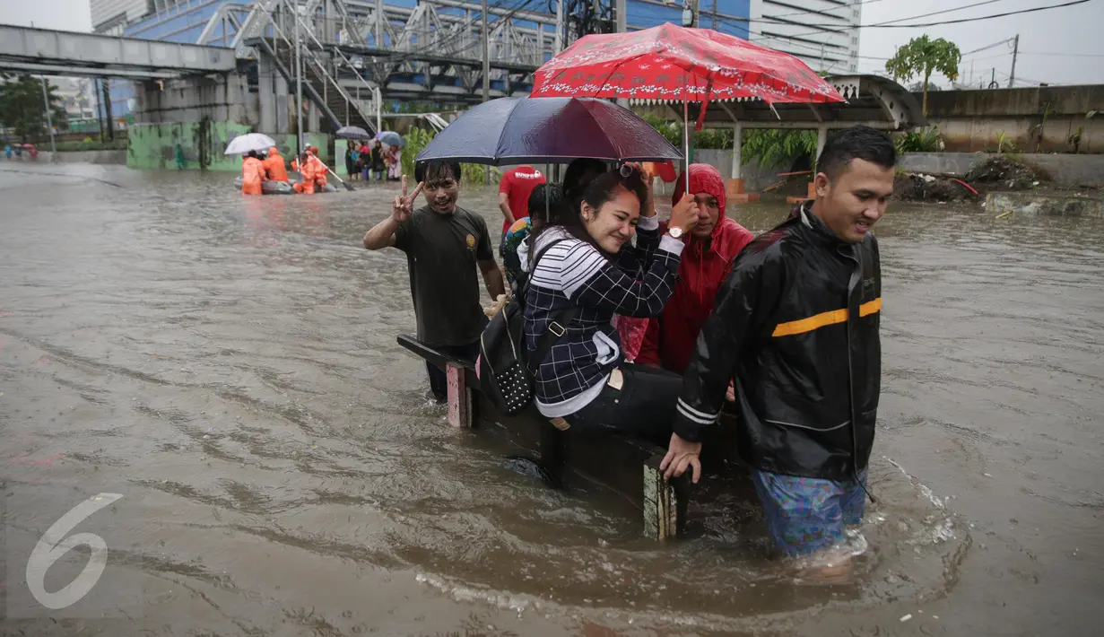 Sejumlah orang memanfaatkan jasa gerobak untuk menyeberangi banjir yang merendam Jalan Gunung Sahari, Jakarta Pusat, Selasa (21/2). Hujan deras yang mengguyur sejak Selasa dini hari membuat sebagian wilayah di Jakarta banjir. (Liputan6.com/Faizal Fanani)