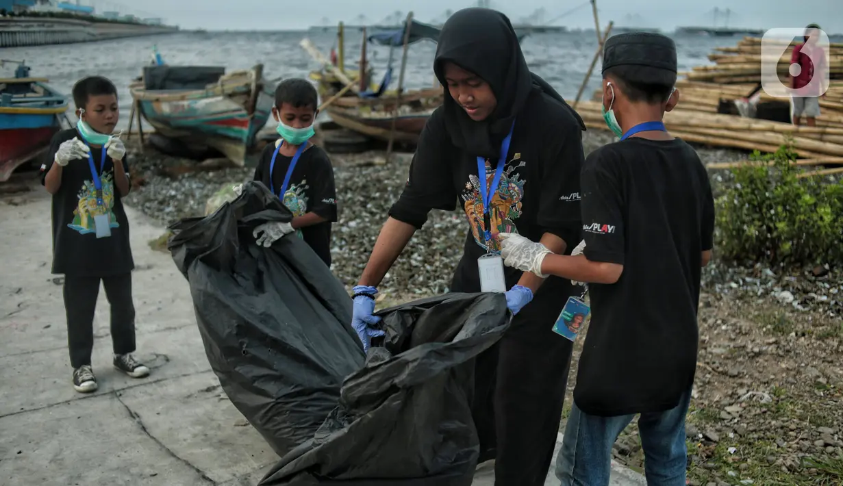 Anak-anak pesisir dan sukarelawan saat membersihkan sampah di Pemukiman Nelayan Manunggal, Cilincing, Jakarta Utara, Minggu (18/9/2022). Tumpukan sampah yang berserakan di kawasan pemukiman nelayan Manunggal, Cilincing menginisasi Kelas Jurnalis Cilik untuk membersihkan sampah dan mengedukasi kepada anak-anak pesisir serta masyarakat pentingnya menjaga kebersihan di lingkungan sekitar. (merdeka.com/Iqbal S. Nugroho)