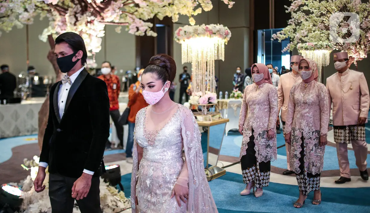 Pemakaian masker untuk pengantin dan keluarga pengantin saat simulasi penerapan protokol kesehatan resepsi pernikahan di era new normal di Jakarta, Kamis (9/7/2020). (Liputan6.com/Faizal Fanani)