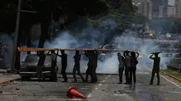 Para demonstran berlindung selama bentrokan antara anggota oposisi dan pasukan polisi di Caracas, Venezuela, (4/4). Mereka menuntut pemerintah menggembalikan kekuasaan kepada pihak opesisi. (AP Photo / Fernando Llano)