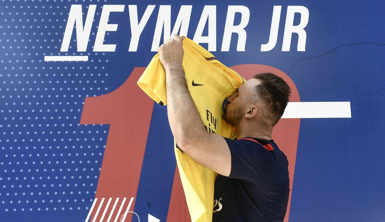 Fans mencium jersey pemain baru Paris Saint Germain, Neymar Jr, di toko merchandise di Paris, Jumat (4/8/2017). Setelah resmi bergabung dengan Paris Saint Germain, jersey Neymar Jr langsung diburu suporter klub Ibu kota. (AFP/Philippe Lopez)
