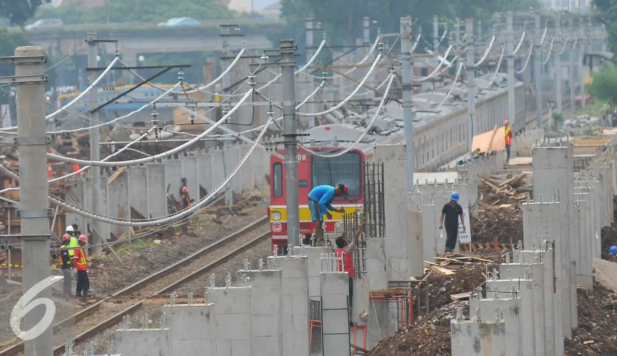 Sebuah Kereta Rel Listrik (KRL) melaju di samping proyek jalur kereta menuju bandara Soetta di kawasan Sudirman, Jakarta, Senin (21/11). Nantinya jalur ini akan digunakan untuk melayani penumpang dari dan menuju bandara Soetta. (Liputan6.com/Angga Yuniar)