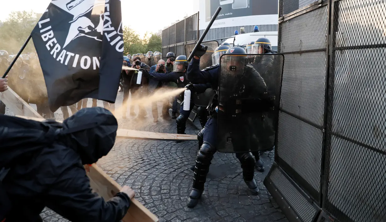 Pasukan anti-huru hara menyemprotkan caiaran kepada demonstran anti-fasis saat mereka menggelar aksinya di Paris (23/4). Bentrokan antara aparat dan demonstran ini terjadi usai pengumuman hasil perolehan suara Pemilu Prancis. (AFP/Thomas Samson)