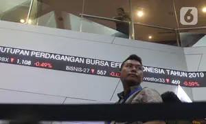 Pengunjung melintas dilayar pergerakan saham di BEI, Jakarta, Senin (30/12/2019). Pada penutupan IHSG 2019 ditutup melemah cukup signifikan 29,78 (0,47%) ke posisi 6.194.50. (Liputan6.com/Angga Yuniar)