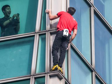 Seorang penghuni gedung merekam aksi atlet panjat tebing 'free solo' asal Amerika, Alex Honnold saat memanjat gedung Taipei 101 tanpa tali pengaman di Taipei, Minggu (25/01/2026). (AFP/I-Hwa Cheng)