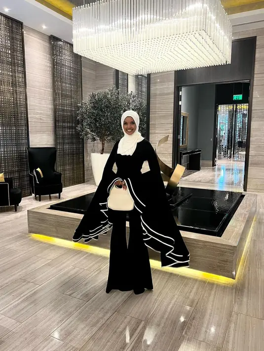 Halima Aden kembali tampil dengan outfit unik. Atasan hitam dengan detail lengan super lebar dan flowy ke bawah, dipadunya juga dengan celana panjang hitam. [Foto: Instagram/halima]