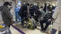 Seorang pria mendorong kerabatnya yang kesakitan di kursi roda saat pasien menerima infus di bangsal darurat sebuah rumah sakit di Beijing, Kamis (5/1/2023). Pasien, kebanyakan dari mereka lansia, berbaring di tandu di lorong dan menerima oksigen sambil duduk di kursi roda saat kasus COVID-19 melonjak di ibu kota China, Beijing. (AP Photo/Andy Wong)