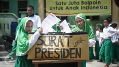 Murid Madrasah Ibtidayah (MI) Yayasan Nurul Bahri memasukan surat yang telah ditulis untuk Presiden Jokowi, di perkampungan nelayan Muara Angke, Jakarta, Senin (27/2). Gerakan Ayo Menulis ini digagas Standarpen Industries. (Liputan6.com/Faizal Fanani)