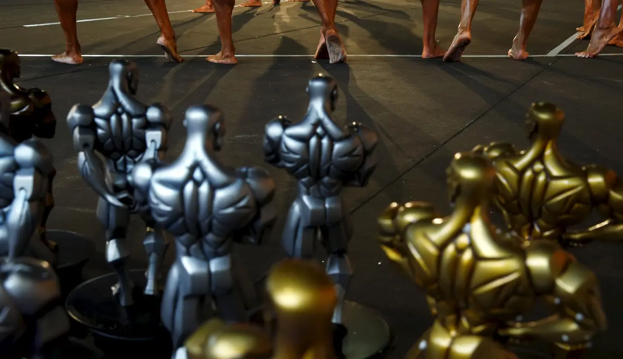 Peserta binaraga melenturkan kaki dibelakang deretan tropi yang akan diperebutkan pada acara kontes Arnold Klasik Eropa 2015 di Madrid, Spanyol, Jumat (25/9). (REUTERS/Susana Vera)