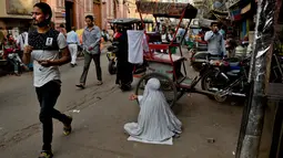Seorang wanita mengemis di pinggir jalan di tempat-tempat tua di New Delhi, India, Rabu (10/10). Banyak warga miskin India bermigrasi ke kota-kota besar untuk mencari pekerjaan. (AP Photo / R S Iyer)