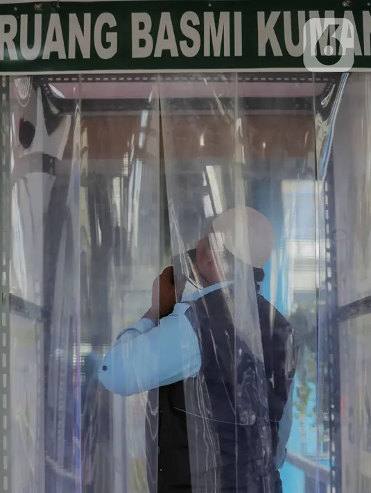 Seorang petugas berada di dalam bilik disinfektan di Halte Transjakarta Harmoni, Jakarta, Selasa (7/4/2020). Pemasangan bilik disinfektan tersebut sebagai upaya pencegahan penyebaran virus Corona COVID-19 di lingkungan Halte Transjakarta. (Liputan6.com/Faizal Fanani)