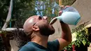 Seorang pria meminum arak dari kendi kaca tradisional selama perayaan minuman beralkohol Lebanon di Kota Taanayel, 8 September 2018. Arak khas Lebanon tersebut berwarna putih susu. (AP Photo/Hussein Malla)