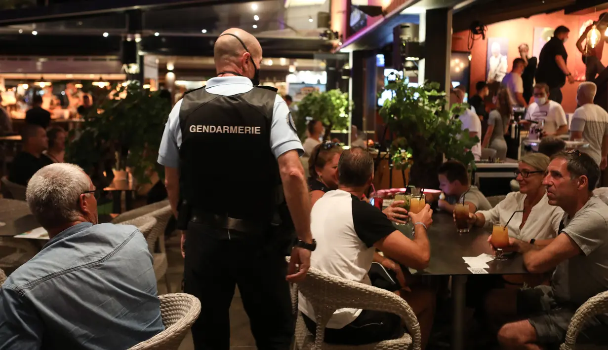 Polisi Prancis berpatroli di sebuah bar untuk mengontrol penggunaan masker di jalan-jalan Argeles-sur-Mer, Rabu (13/8/2020). Pemakaian masker di beberapa area ramai di sekitar Paris merupakan kewajiban sebagai upaya untuk membendung peningkatan tajam infeksi covid-19. (RAYMOND ROIG/AFP)