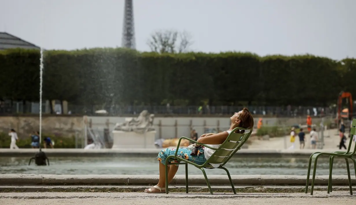<p>Seorang wanita menikmati matahari saat suhu yang diperkirakan akan naik di Taman Tuileries, Paris, Prancis, 10 Juli 2023. (AP Photo/Thomas Padilla)</p>