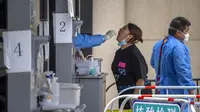Pekerja menyeka tenggorokan seorang wanita di tempat pengujian virus corona COVID-19 pada hari ketiga tes massal untuk jutaan penduduk di Distrik Chaoyang, Beijing, China, 15 Juni 2022. (AP Photo/Mark Schiefelbein)