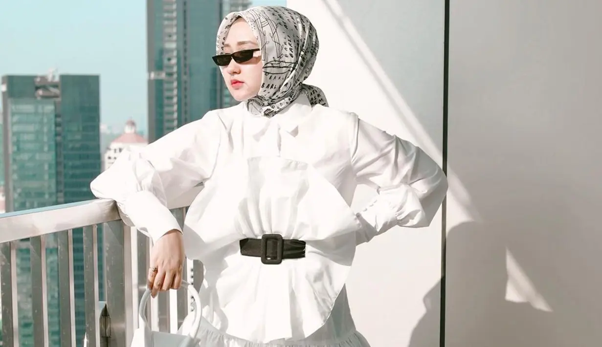 Tampil dengan busana casual berwarna putih, Dian Pelangi memadukannya dengan hijab putih bercorak hitam yang disesuaikan dengan ikat pinggang serta kacamata. Gaya ibu satu anak ini terlihat begitu menawan. (Liputan6.com/IG/@dianpelangi)
